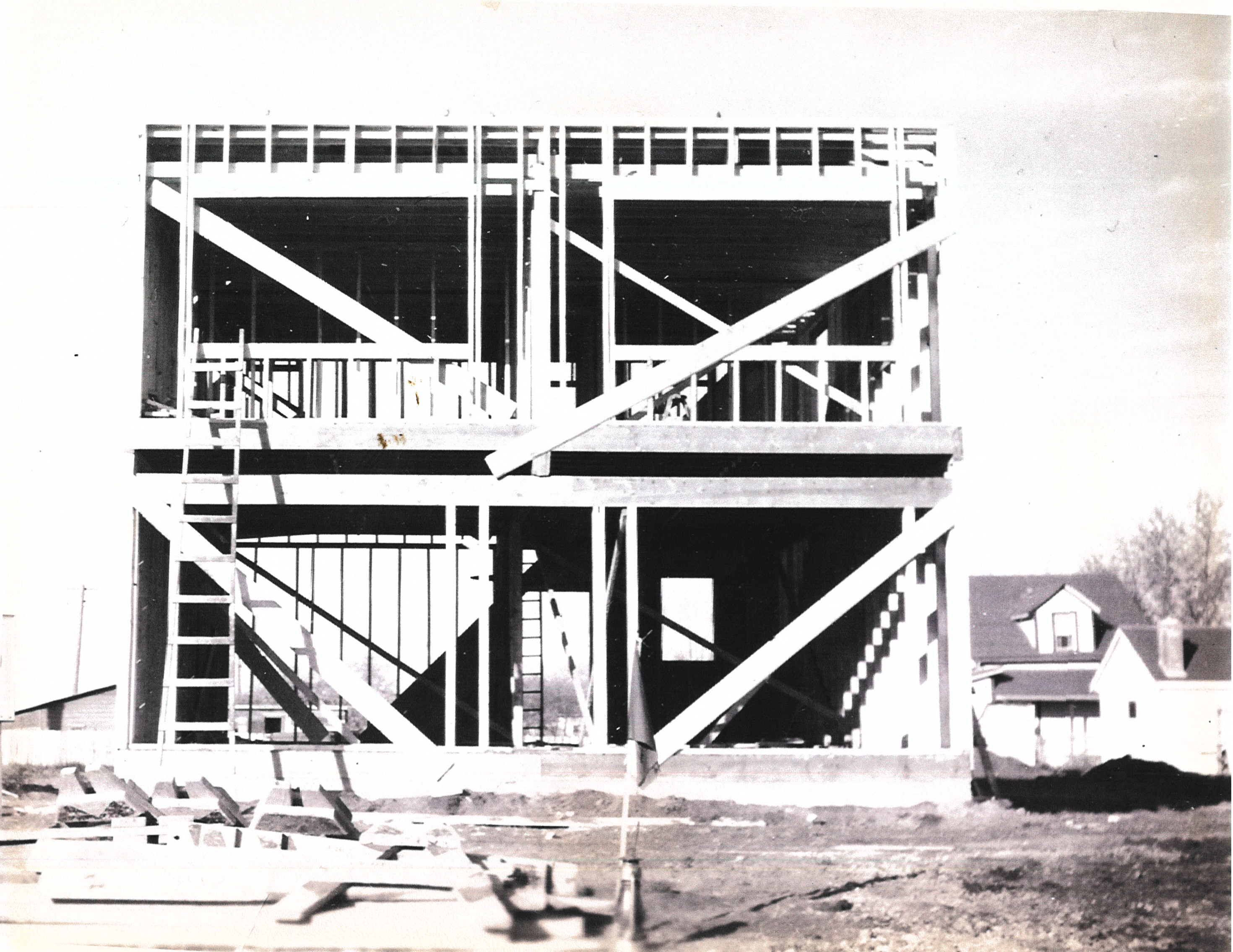 The building under construction, wood framing visible, 1954